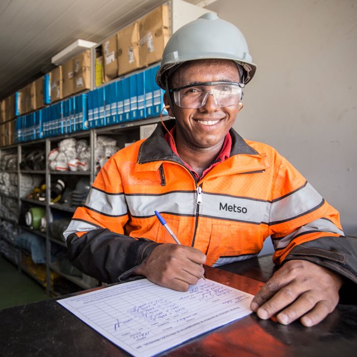 Man in working gear and helmet smiling at the camera.