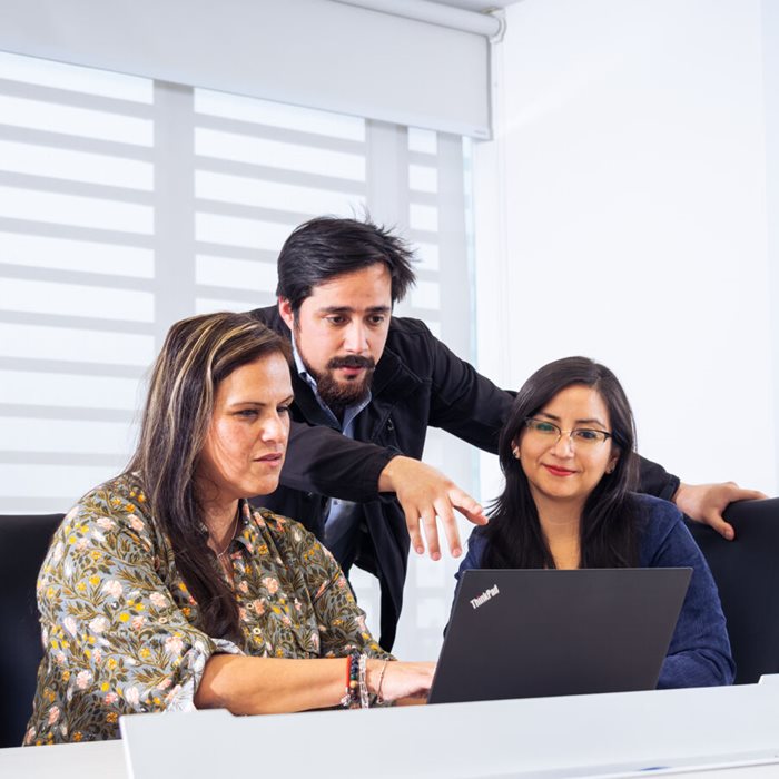 Three colleagues looking at a laptop.