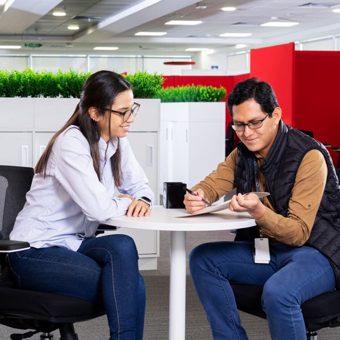 Two colleagues sitting at an office desk looking at documents.